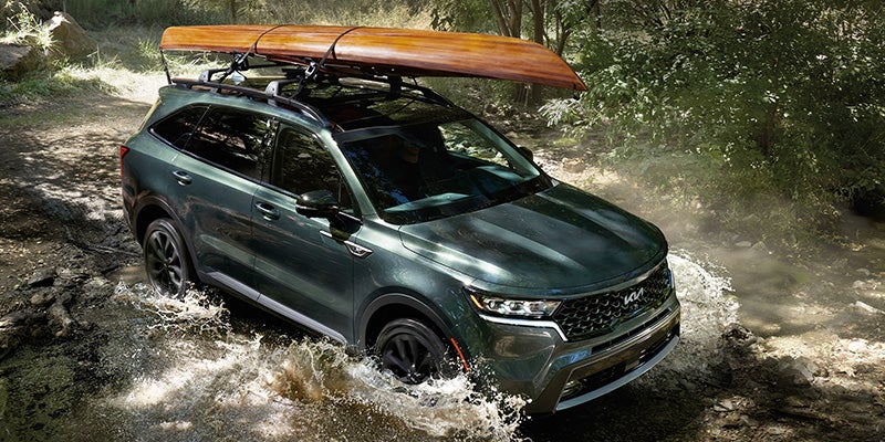 2022 Kia Sorento with a kayak driving through a river.